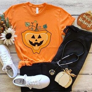 May include: Orange t-shirt with a jack-o'-lantern graphic and the text "Happy Harvest".
