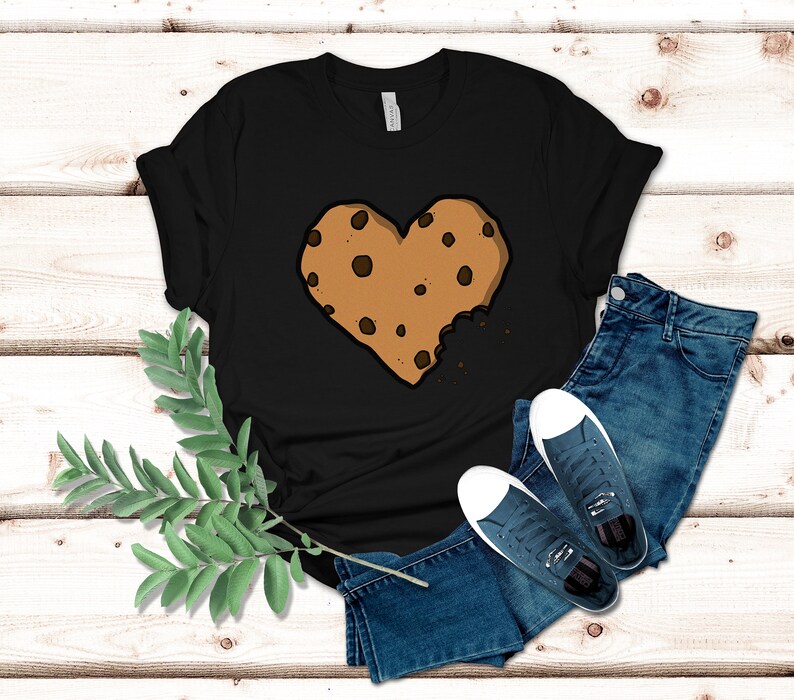 May include: Black t-shirt with a brown chocolate chip cookie in the shape of a heart with a bite taken out of it.