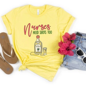 May include: Yellow t-shirt with the text "Nurses need shots too" and a cartoon image of a bottle of tequila and a shot glass.