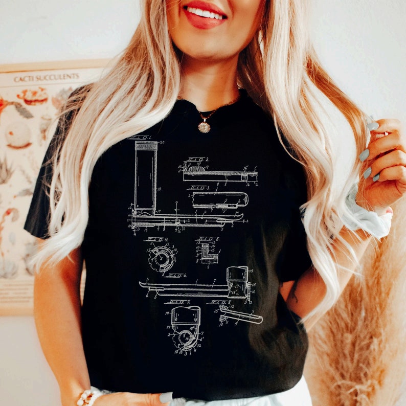 Peut inclure: T-shirt noir avec un graphique blanc d'un dessin de brevet vintage pour un chariot &eacute;l&eacute;vateur. Le dessin comprend des num&eacute;ros et des &eacute;tiquettes.