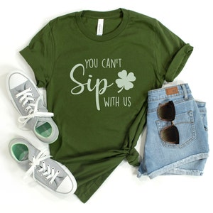 May include: A green t-shirt with the text "You Can't Sip With Us" and a four-leaf clover graphic.