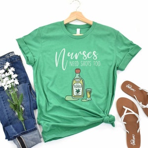 May include: Green t-shirt with the text "Nurses Need Shots Too" and a cartoon image of a bottle of tequila and a shot glass.
