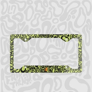 Green and black f1 themed lando norris car license plate frame is shown against a black and white lando norris pattern. Personalised racing number 4 is on the bottom of the frame in orange and black text outline. 

Lando Norris F1 License Plate Frame: Green and black pattern, Aluminum