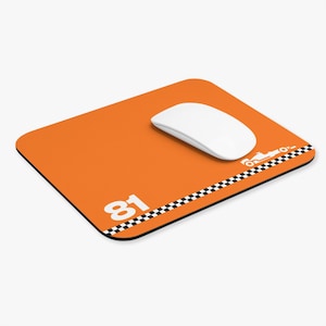 May include: Orange mousepad with a white computer mouse. The mousepad features the number 81 in white, a checkered flag design, and a white race car graphic. The mousepad is rectangular.