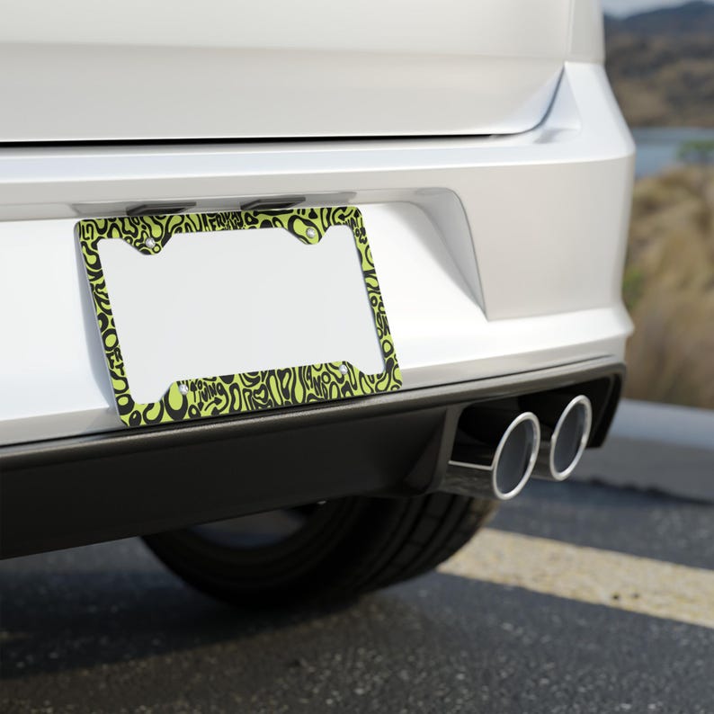 Rear license plate of a white car with exhaust piping. Green and black f1 themed lando norris car license plate frame is on the car.

Lando Norris F1 License Plate Frame: Green and black pattern, Aluminum