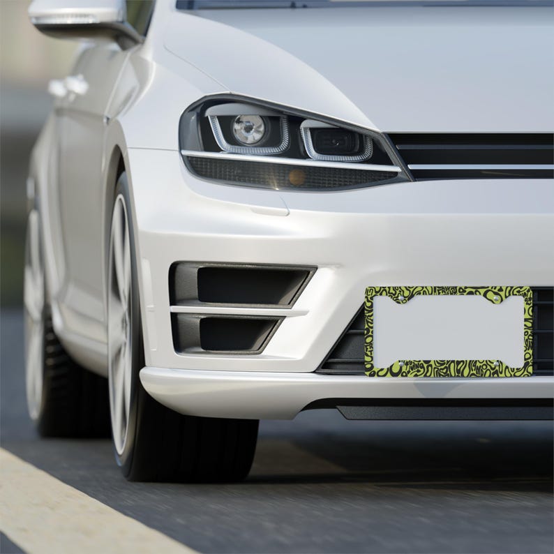 Lando Norris F1 License Plate Frame: Green and black pattern, Aluminum. 
Frame is on the front of a white silver car.