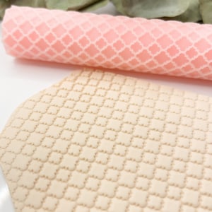 Könnte beinhalten: Nahaufnahme eines beigefarbenen, strukturierten Silikon-Nudelholzes mit einem sich wiederholenden geometrischen Muster. Das Nudelholz wird verwendet, um dekorative Muster auf Fondant oder Ton zu erstellen.