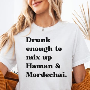May include: White t-shirt with black text that reads "Drunk enough to mix up Haman & Mordechai."