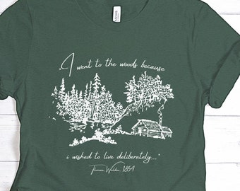 May include: A green t-shirt with a white illustration of a cabin in the woods. The text "I went to the woods because I wished to live deliberately..." is printed on the shirt, along with the author's name "Thoreau, Walden, 1854".