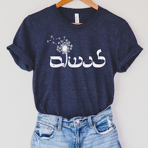 May include: A navy blue t-shirt with a white dandelion graphic and the Arabic word "dad" in white lettering.