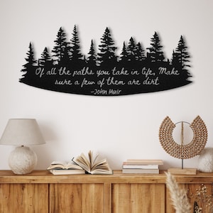 Cartel de metal con cita de John Muir: "De todos los caminos que tomes en la vida, asegúrate de que algunos de ellos sean de tierra"