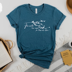 May include: A teal blue t-shirt with a white graphic design of a tree branch with birds and the text "The earth has music for those who listen."