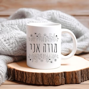 May include: White ceramic mug with a black floral design and the Hebrew text "Good morning" on the front.