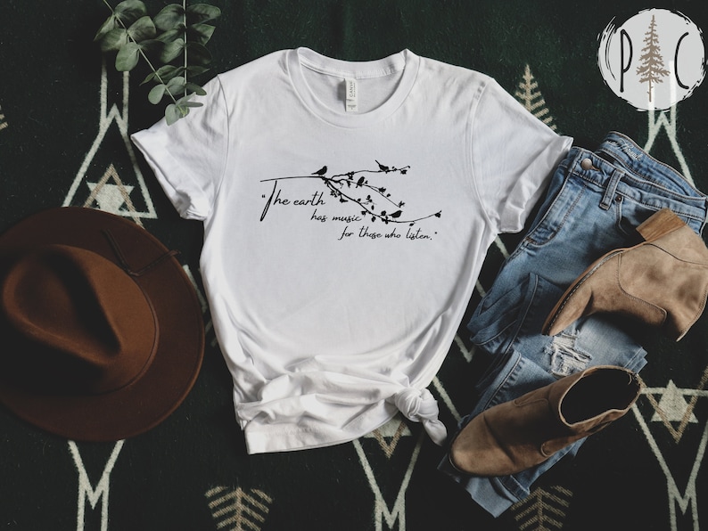 May include: White t-shirt with a black graphic of a branch with birds and the text "The earth has music for those who listen."