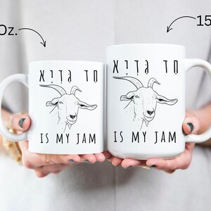 May include: Two white ceramic mugs with black text and a goat illustration. The text on the mugs reads "חד גִדְיָא חד גִדְיָא IS MY JAM". The mug on the left is 11 ounces and the mug on the right is 15 ounces.