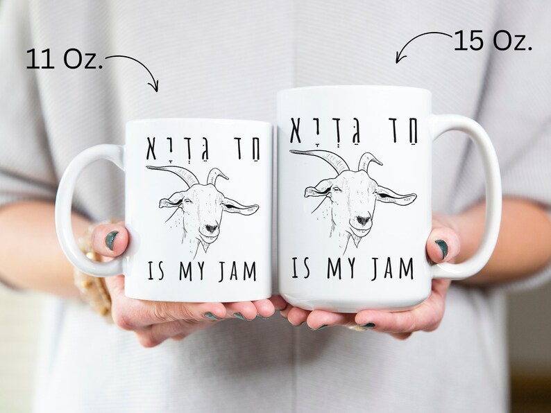 May include: Two white ceramic mugs with black text and a goat illustration. The text on the mugs reads "חד גִדְיָא חד גִדְיָא IS MY JAM". The mug on the left is 11 ounces and the mug on the right is 15 ounces.