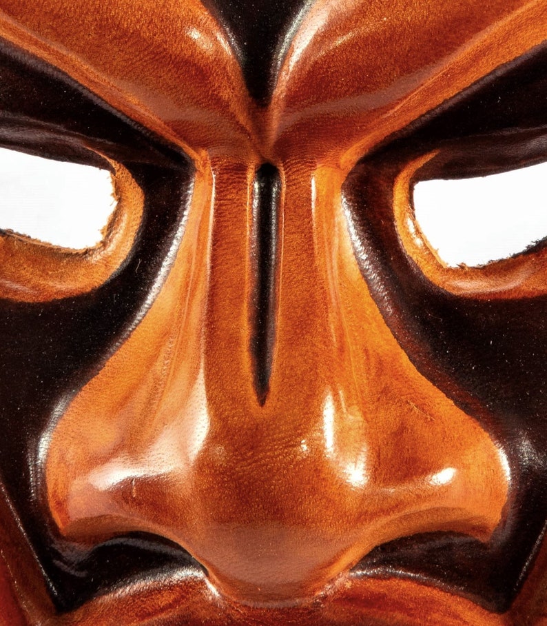 Puede incluir: Primer plano de una m&aacute;scara de cuero con una expresi&oacute;n feroz. La m&aacute;scara est&aacute; pintada en tonos marrones y negros, con una nariz prominente y ojos exagerados.