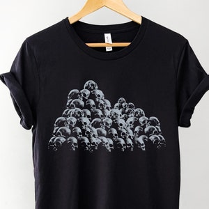 May include: Black t-shirt with a graphic print of a pile of skulls.