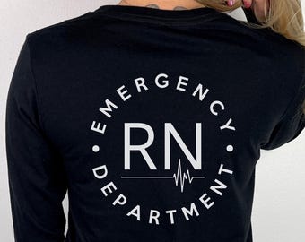 May include: A black long-sleeve shirt featuring a white circular graphic on the back. The text reads EMERGENCY DEPARTMENT in a circle, with the letters RN in the center above a horizontal line that transitions into a heartbeat EKG rhythm line.