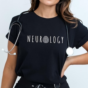 K&ouml;nnte beinhalten: Schwarzes T-Shirt mit dem Wort "NEUROLOGY" in Wei&szlig; und einer Gehirngrafik. Ein Stethoskop ist um den Hals gelegt. Das T-Shirt wird von einer Person getragen. Das Wort "BLACK" ist unten rechts sichtbar.