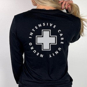 May include: Black long-sleeve shirt with a white graphic of a cross inside a circle with the text "Neuro Intensive Care Unit" around it.