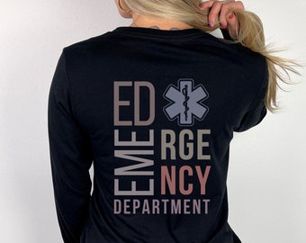 May include: A black long-sleeve shirt featuring a graphic on the back with the text ED, RGE, NCY, and DEPARTMENT in muted tones. The design includes a Star of Life symbol with a serpent and staff emblem positioned next to the letters ED.