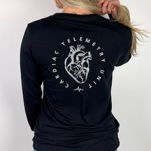 May include: Black long-sleeve shirt with a white graphic of a heart and the text "Cardiac Telemetry Unit" in a circle.