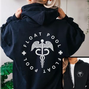 Peut inclure: Sweat à capuche bleu marine avec un motif circulaire blanc au dos. Le motif comprend les mots "FLOAT POOL" autour d'un symbole médical. Le sweat à capuche a une capuche et un cordon de serrage.