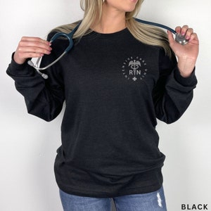 May include: Black long-sleeve shirt with a silver graphic of a medical symbol and the text "INTENSIVE CARE UNIT RN".