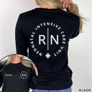 May include: A black long-sleeve shirt featuring a white graphic on the back with the text Neonatal Intensive Care Unit surrounding the letters RN and a small cross symbol. The front includes the name Amanda and a smaller version of the graphic.