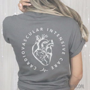 May include: Charcoal gray t-shirt with a white anatomical heart design inside a circular text that reads "CARDIOVASCULAR INTENSIVE CARE". A heartbeat line is below the heart graphic. The word "CHARCOAL" is at the bottom right.