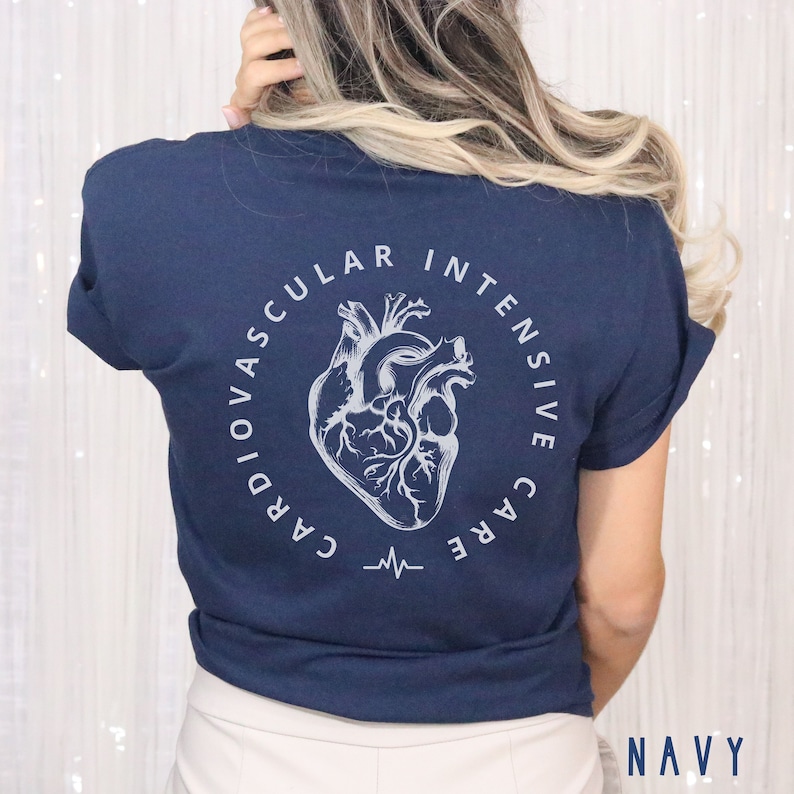 May include: A navy blue t-shirt with a white graphic of a heart and the text 'Cardiovascular Intensive Care' in a circle around the heart. The text is in a white, sans-serif font. The t-shirt is displayed on a model. The text 'NAVY' is displayed in white at the bottom of the image.