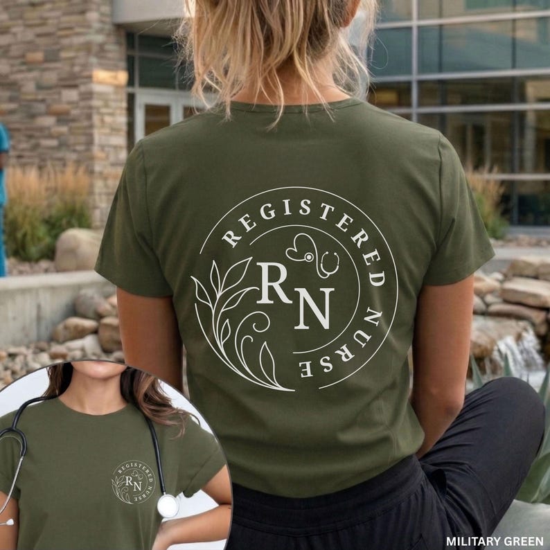 Puede incluir: Camiseta verde oliva con un dise&ntilde;o circular blanco que incluye las palabras "REGISTERED NURSE" y las letras "RN" con un estetoscopio y detalles florales. La camiseta es de manga corta y tiene cuello redondo.