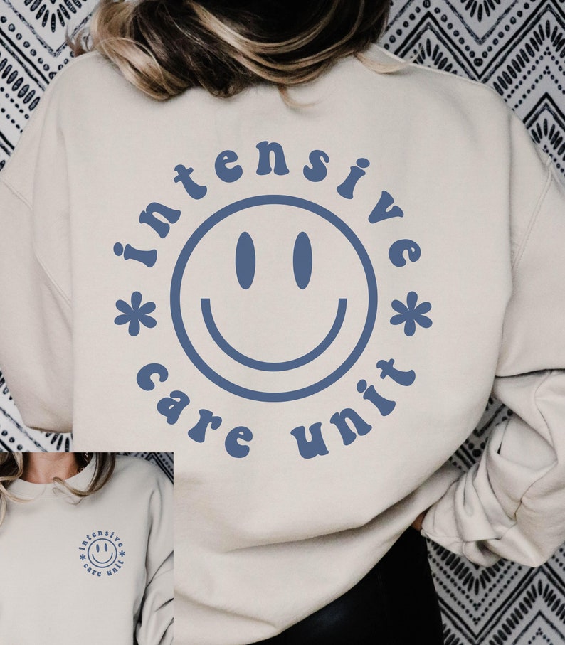 May include: A beige sweatshirt with a blue smiley face graphic and the text "intensive care unit" around the smiley face.