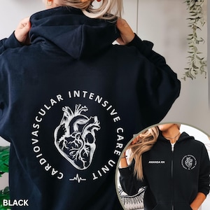 May include: A black zip-up hoodie featuring a white anatomical heart graphic on the back surrounded by the text "CARDIOVASCULAR INTENSIVE CARE UNIT". The front displays the text "AMANDA RN" on the right chest and a smaller heart graphic on the left.
