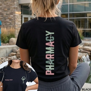May include: A black t-shirt featuring the word PHARMACY printed vertically in sage green and dusty pink on the back. The front displays the text Katelyn CPhT and a medical caduceus symbol in a matching dusty pink color on the left chest area.