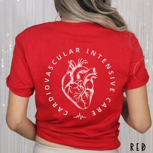 May include: Red t-shirt with a white graphic of a heart and the words "CARDIOVASCULAR INTENSIVE CARE" in a circle. Below the heart is a white EKG line. The word "RED" is in the bottom right corner.