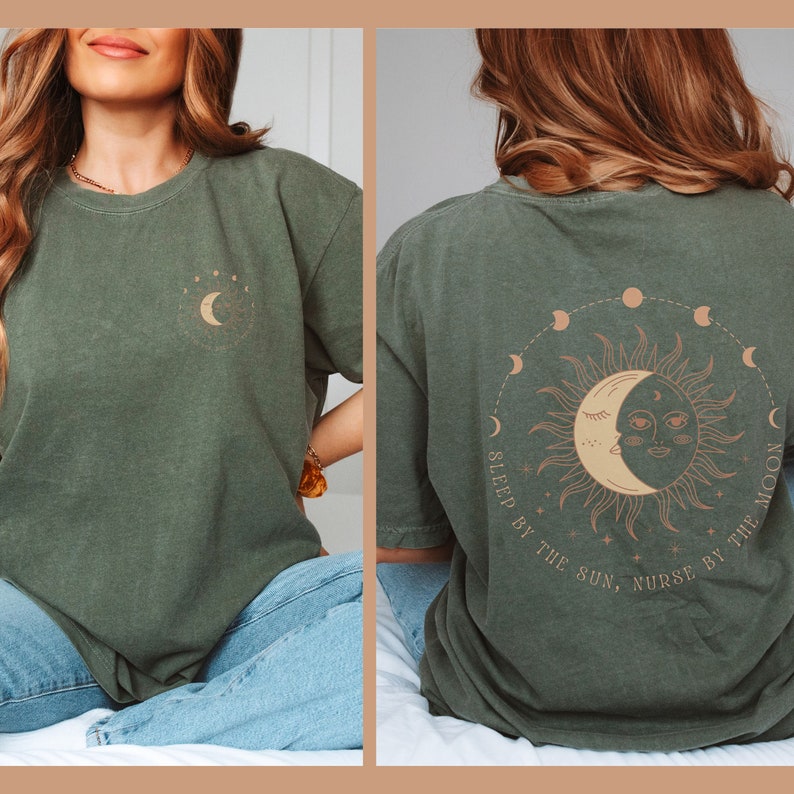 May include: Olive green t-shirt with a celestial design. The front features a crescent moon and stars. The back displays a sun and moon graphic with the text "SLEEP BY THE SUN, NURSE BY THE MOON" in a circular pattern.