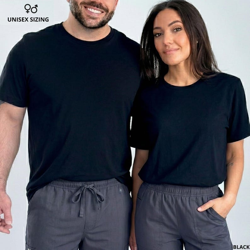 Pode incluir: Duas pessoas vestindo camisetas pretas com gola redonda e cal&ccedil;as cinza com cord&atilde;o. O texto "UNISEX SIZING" est&aacute; acima da imagem. A palavra "BLACK" est&aacute; no canto inferior direito.