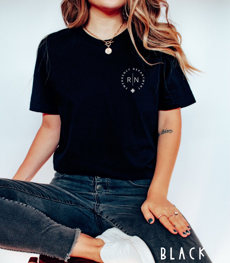 May include: Black t-shirt with a white circular design that reads "Emergency Department" and "RN" with a cross symbol. The word "BLACK" is at the bottom of the image. The shirt is paired with dark wash jeans and white sneakers.