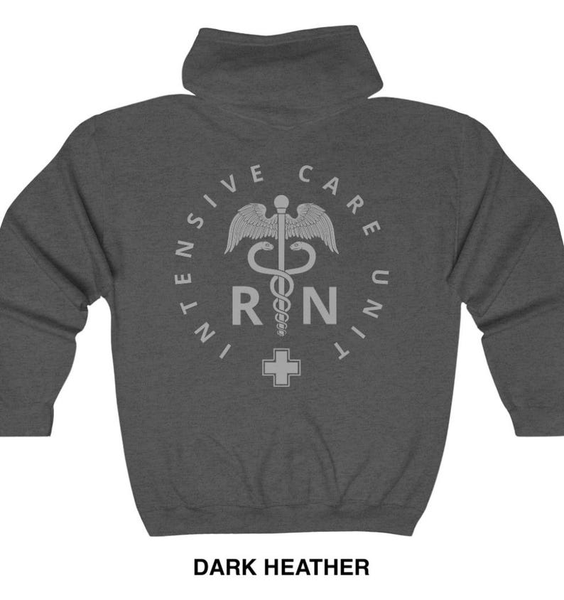 Peut inclure: Sweat-shirt &agrave; capuche gris chin&eacute; fonc&eacute; avec un motif blanc repr&eacute;sentant un symbole m&eacute;dical, un serpent enroul&eacute; autour d'un b&acirc;ton, avec les lettres "RN" et une croix. Le texte autour du symbole est "Intensive Care Unit".