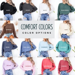 May include: A collage of long-sleeved sweatshirts in various colors, including black, pepper, white, blue spruce, espresso, ivory, denim, blue jean, chambray, seafoam, orchid, blossom, watermelon, and crimson. The text "COMFORT COLORS COLOR OPTIONS" is displayed.