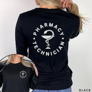 May include: Black long-sleeve shirt with a white circular design on the back that reads "PHARMACY TECHNICIAN" around a caduceus symbol. The shirt is made of a soft material and is suitable for everyday wear.