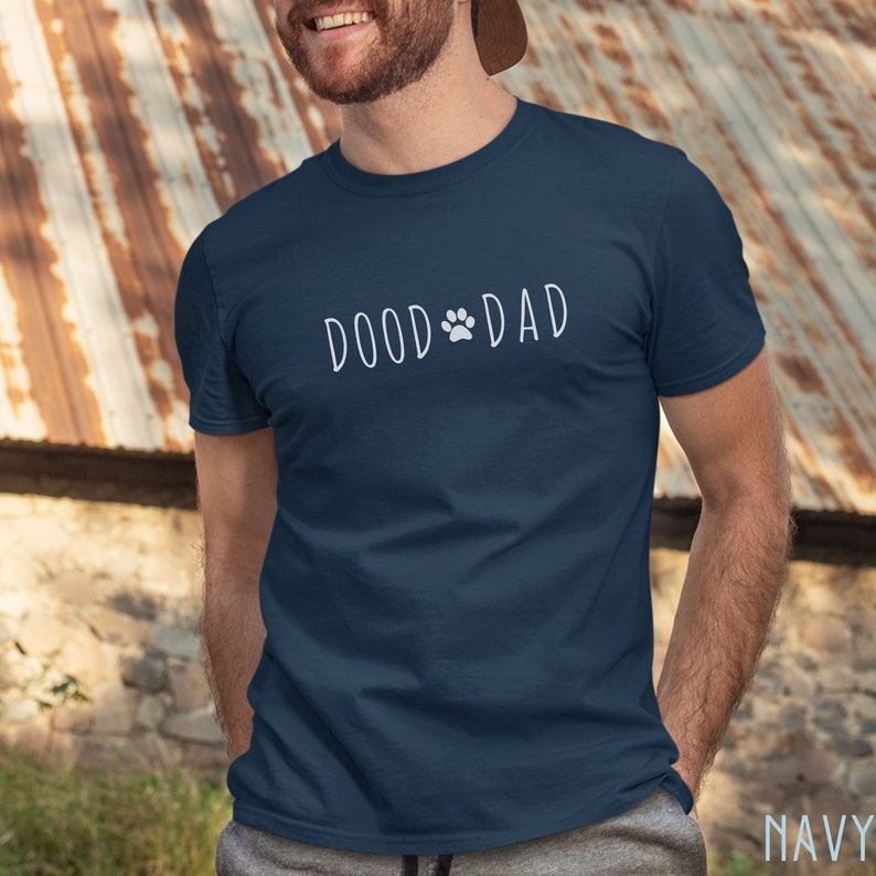 May include: A navy blue t-shirt with the text 'DOOD DAD' in white with a paw print between the words.