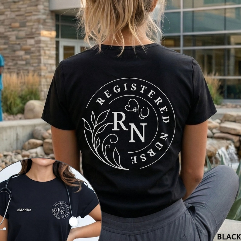 Puede incluir: Camiseta negra con un dise&ntilde;o circular blanco en la espalda. El dise&ntilde;o incluye las palabras "REGISTERED NURSE", las letras "RN", un estetoscopio y elementos florales. La camiseta la lleva una persona.