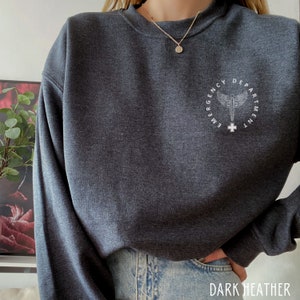 May include: Dark heather grey sweatshirt with a white graphic of a medical caduceus inside a circle with the text "Emergency Department" around it.