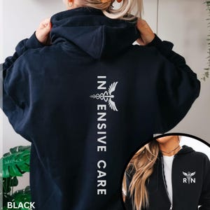 May include: Black hoodie with white text and a medical symbol. The words "INTENSIVE CARE" are vertically aligned on the back. A smaller image shows a front view of a black zip-up hoodie with the same symbol and "RN" text.