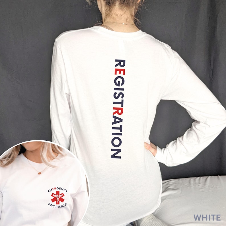 Puede incluir: Una camiseta blanca de manga larga con la palabra REGISTRATION impresa verticalmente en azul oscuro y rojo en la espalda. El pecho muestra un peque&ntilde;o s&iacute;mbolo m&eacute;dico de caduceo rojo rodeado por el texto EMERGENCY DEPARTMENT.