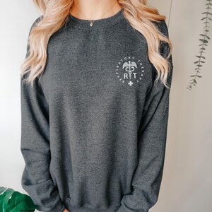 May include: A dark gray sweatshirt with a white graphic of a respiratory therapist symbol and the text "Respiratory Therapy" around it.