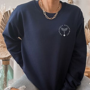May include: A navy blue sweatshirt with a white graphic of a medical symbol and the text "Emergency Department".